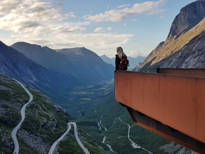 Vrouw met rugzak op het Trollstigen uitkijkpunt bij zonsondergang