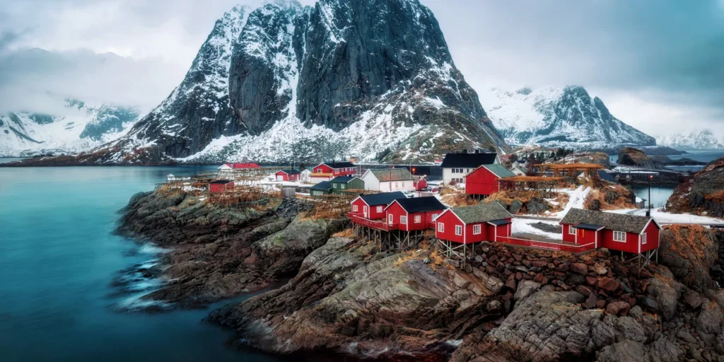 Rode rorbuer aan het water onder besneeuwde bergen op de Lofoten