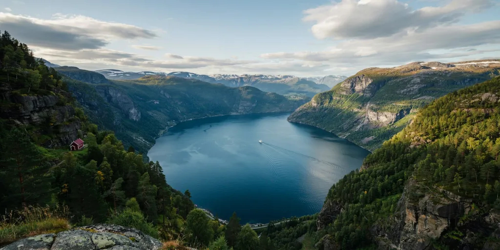 Uitzicht over een Noors fjord met een rood houten huisje op de helling